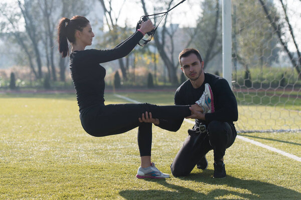 Young Couple Doing Trx Straps Exercise in Park