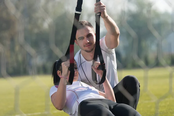 Attraente coppia facendo Trx cinghie formazione in parco — Foto Stock