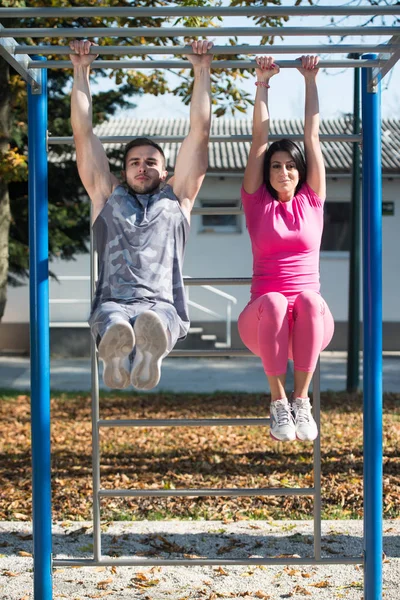 Séduisant couple exercice avec trempettes Bar dans le parc — Photo