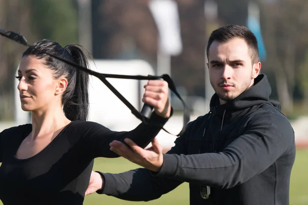 Attraente coppia facendo Trx cinghie formazione in parco — Foto Stock