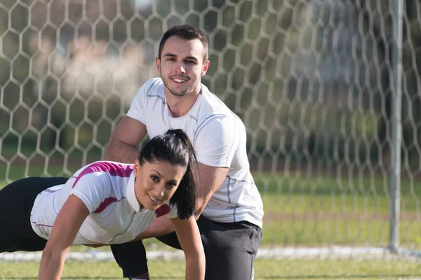 Casal jovem exercitando correias Trx no parque — Fotografia de Stock