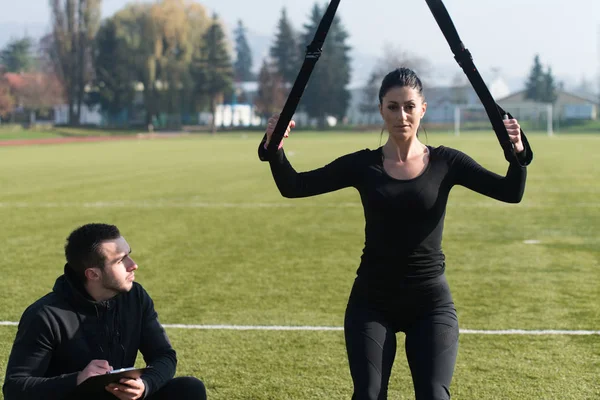 Jeune couple exerçant des sangles Trx dans le parc — Photo