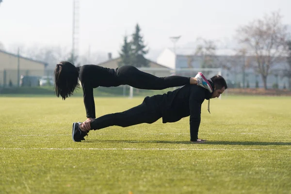 Casal atraente fazendo flexões no parque — Fotografia de Stock