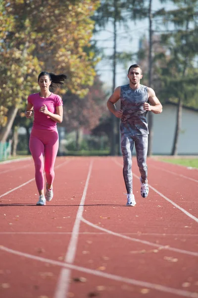 Atleta pareja corriendo en la pista de atletismo —  Fotos de Stock