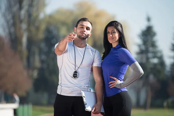 Personal Trainer toma notas enquanto a mulher se exercita ao ar livre — Fotografia de Stock