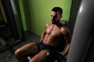 Yapan erkek bacak bukleler egzersiz spor salonunda oturmuş