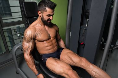 Yapan erkek bacak bukleler egzersiz spor salonunda oturmuş