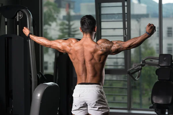 Fisicoculturista modelo de fitness posando bíceps dobles después de los ejercicios —  Fotos de Stock