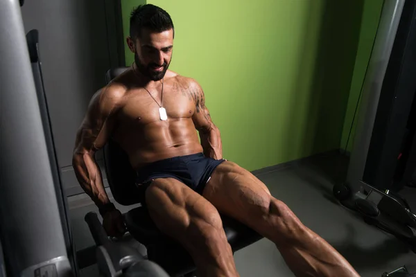 Hombre haciendo ejercicio sentado de los rizos de la pierna en el gimnasio —  Fotos de Stock