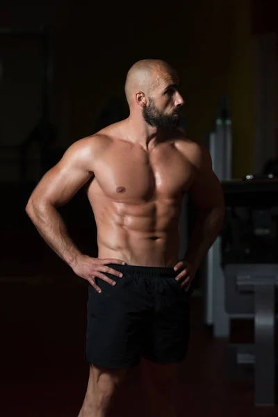 Uomo muscolare che flette i muscoli in palestra — Foto Stock