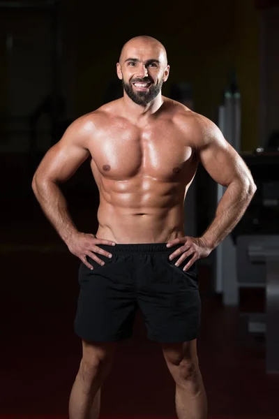 Hombre musculoso guapo flexionando músculos en el gimnasio — Foto de Stock