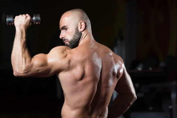 Bodybuilder uitoefening schouders met halter — Stockfoto