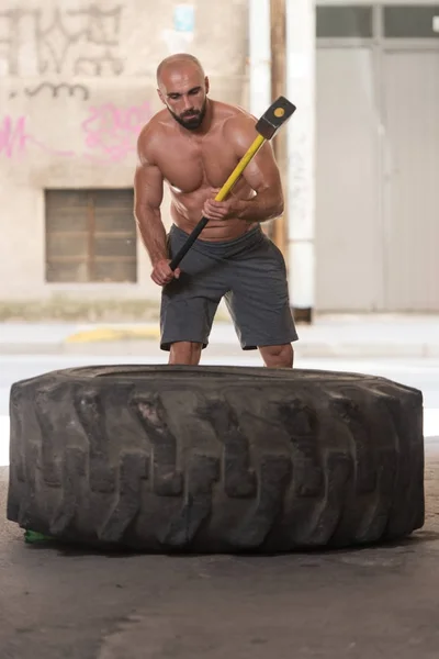 Homme athlétique frappe pneu dans la salle de gym — Photo