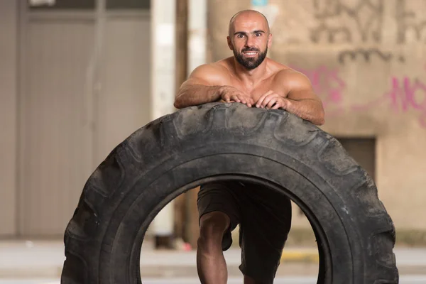 Gespierde Man uitoefening van Crossfit Workout door Tire Flip — Stockfoto