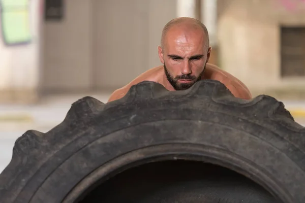 Překlopit svalnatý muž cvičit Crossfit cvičení podle pneumatiky — Stock fotografie