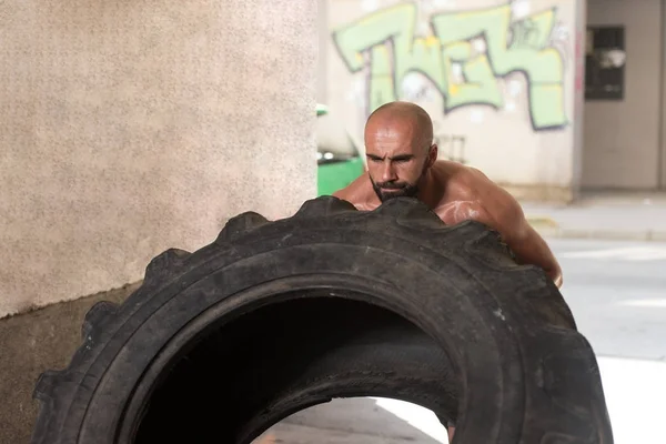 Překlopit svalnatý muž cvičit Crossfit cvičení podle pneumatiky — Stock fotografie