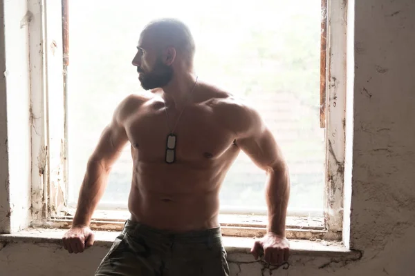 Handsome Man Flexing Muscles In Refuge — Stock Photo, Image