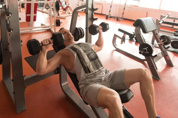 Junger Mann im Fitnessstudio übt Brust mit Hanteln — Stockfoto