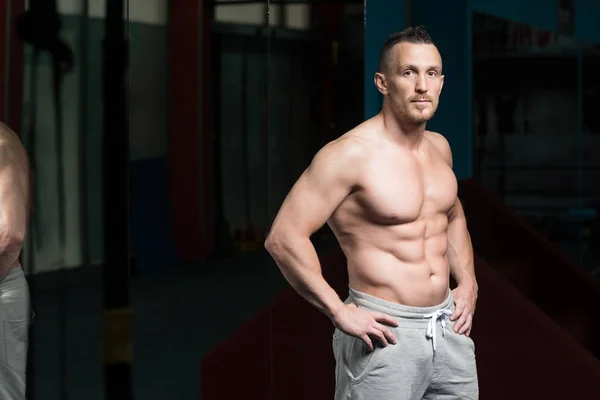 Uomo muscolare che flette i muscoli in palestra — Foto Stock