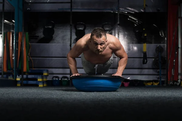 Treinador pessoal fazendo flexões com bola de equilíbrio Bosu — Fotografia de Stock