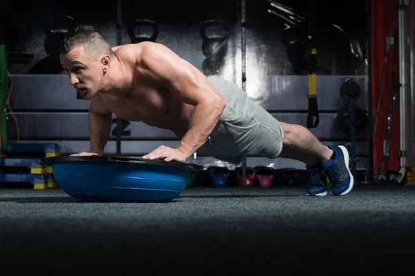 Instrutor pessoal fazendo flexões com bola de equilíbrio Bosu — Fotografia de Stock