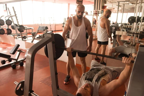Personal Trainer helpt Man op borst oefening — Stockfoto