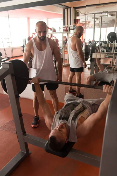 Palestra Coach aiutare l'uomo sul petto esercizio — Foto Stock