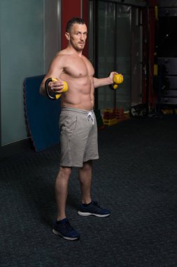 Genç adam su ısıtıcısı çan karanlık bir spor salonu - su ısıtıcısı-bell ile ağır egzersiz yapmak Bodybuilder olan çalışma dışarı