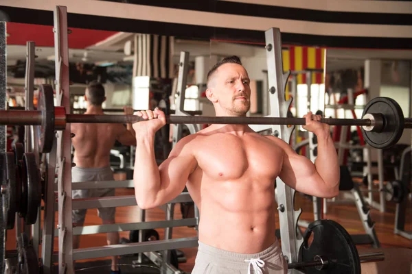 Kaslı adam ağır egzersiz halter salonunda ile omuz için yapmak