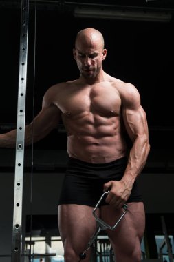 Kablo ile omuz için ağır egzersiz yaparak vücut geliştirmeci