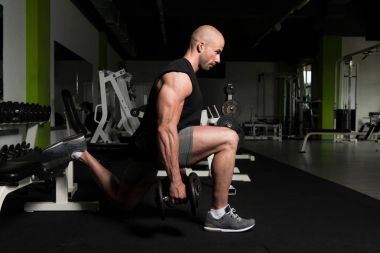 Man Exercising Legs With Dumbbells In The Gym clipart