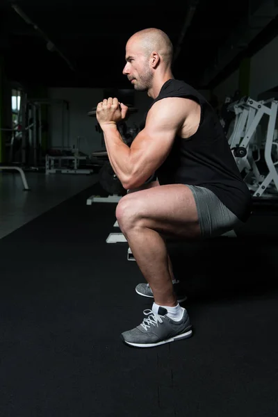 Muskularny mężczyzna ćwiczenia mięśnia czworogłowego z hantlami — Zdjęcie stockowe