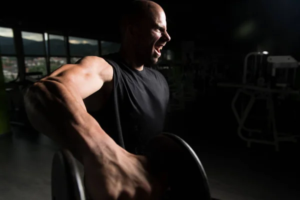 Hombre con sombrillas haciendo ejercicio en los hombros — Foto de Stock