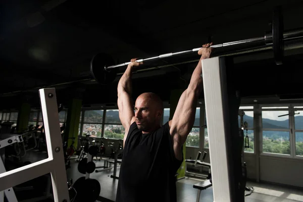 Hombre en el gimnasio Ejercicio de hombro con barra — Foto de Stock