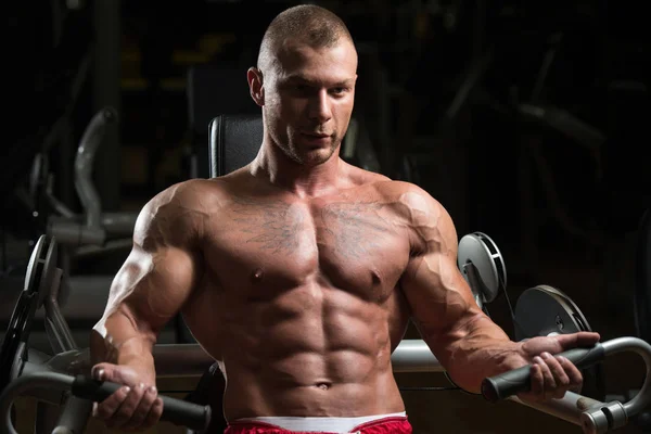 Hombre muscular ejercitando bíceps en la máquina de cable — Foto de Stock