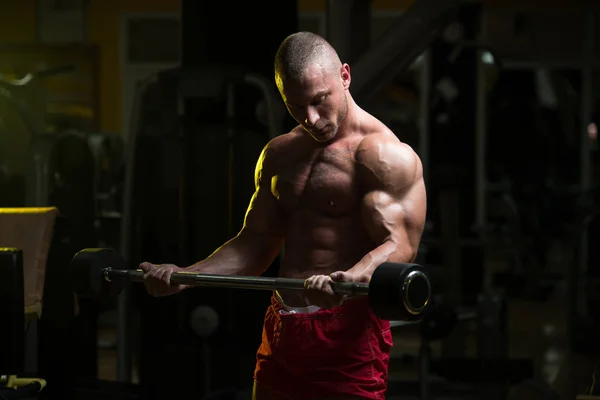 Muskulöser Mann trainiert Bizeps mit Langhantel — Stockfoto