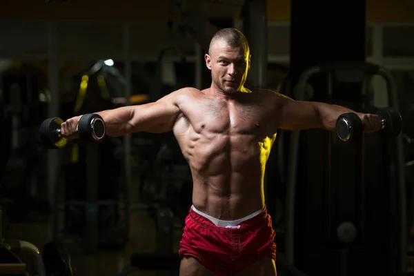 Muž s činkami cvičení ramena — Stock fotografie