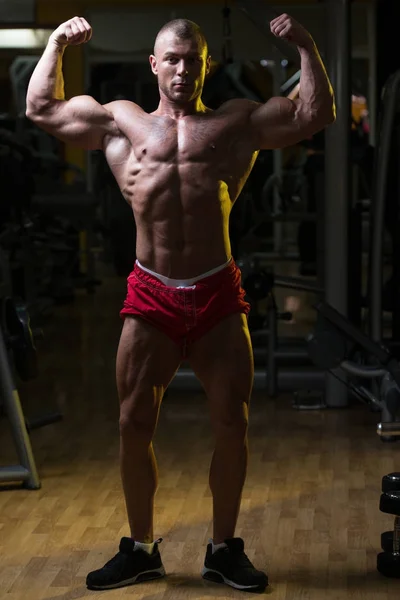 Homem muscular flexionando músculos no ginásio — Fotografia de Stock