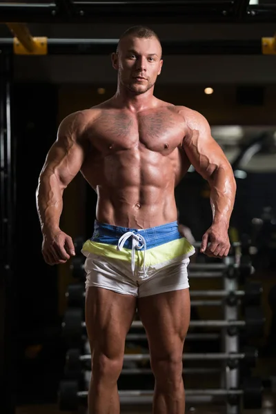 Musculoso hombre flexionando los músculos en el gimnasio —  Fotos de Stock