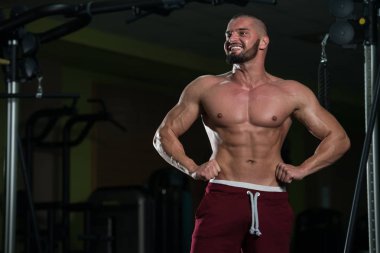 Spor salonu ve kasların esneme - güçlü ayakta sağlıklı genç adam kaslı atletik vücut Fitness Model çalışmaları sonra poz