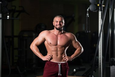 Spor salonu ve kasların esneme - güçlü ayakta sağlıklı genç adam kaslı atletik vücut Fitness Model çalışmaları sonra poz
