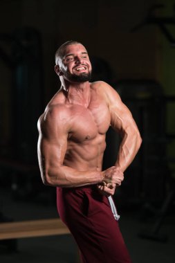 Spor salonu ve kasların esneme - güçlü ayakta sağlıklı genç adam kaslı atletik vücut Fitness Model çalışmaları sonra poz