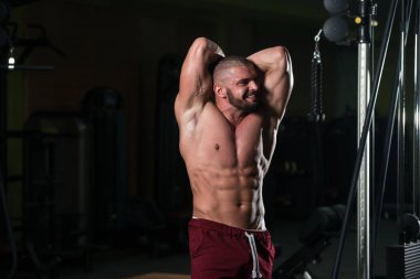 Spor salonu ve kasların esneme - güçlü ayakta sağlıklı genç adam kaslı atletik vücut Fitness Model çalışmaları sonra poz