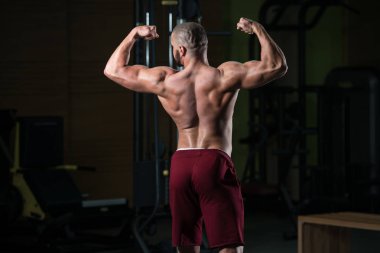 Spor salonu ve kasların esneme - güçlü ayakta sağlıklı genç adam kaslı atletik vücut Fitness Model çalışmaları sonra poz