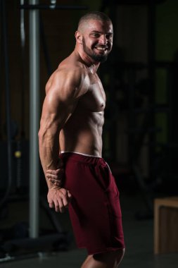 Yakışıklı Genç Adam Spor Salonunda Güçlü Duruyor ve Kaslarını Geriyor - Kas Atletik Vücut Geliştirici Spor Sonrası Spor Pozisyonu