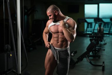 Spor salonu ve kasların esneme - güçlü ayakta sağlıklı genç adam kaslı atletik vücut Fitness Model çalışmaları sonra poz