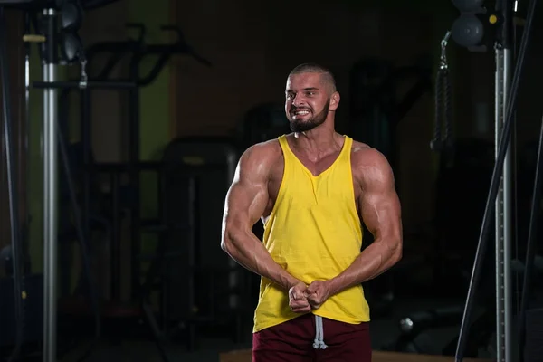 Schöner Junger Mann Der Stark Fitnessstudio Steht Und Die Muskeln — Stockfoto