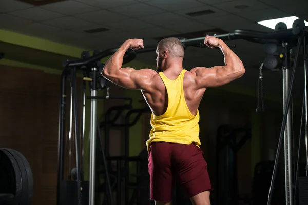 在汗衫与电缆在健身房里的机器上的二头肌锻炼重英俊肌肉健身健美 — 图库照片