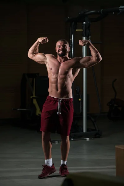 健全な若い男立っているジムと屈曲の筋肉で強い筋肉運動ボディービルダー フィットネス モデルの練習後のポーズ — ストック写真