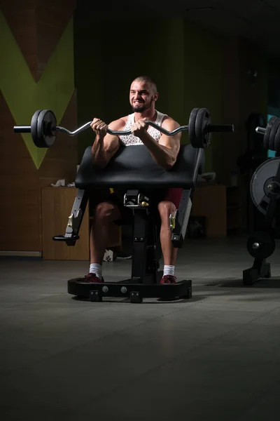 筋肉の男はジムでバーベルとバイセップのための重い重量運動を行う — ストック写真